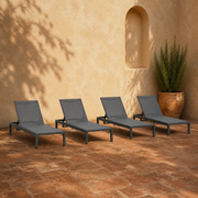 Room 3 | four dark charcoal aluminum chaise lounges with grey mesh sling in a warm plaster courtyard