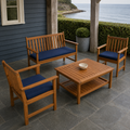 In a room | coastal veranda with natural acacia loveseat, two navy-cushioned armchairs, and coffee table