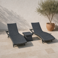 Complete set of two charcoal-gray woven chaise loungers and one matching side table on a limestone terrace