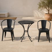 In a room | sunlit limestone courtyard with black iron bistro table and two armchairs