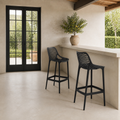 In scale | two black lattice bar stools beside a tall black-framed glass doorway at a pale outdoor bar
