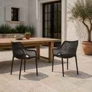 Terrace scale | two matte-black open-mesh armchairs beside a full-height black-framed French door