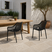 Terrace pair | two matte-black open-mesh armchairs shown together at an outdoor dining table