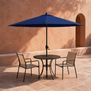In a room | navy octagonal umbrella over black cafe table in terracotta courtyard with two chairs