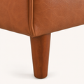 Leg detail | Macro of a tapered brown wood leg meeting the chestnut faux-leather rail