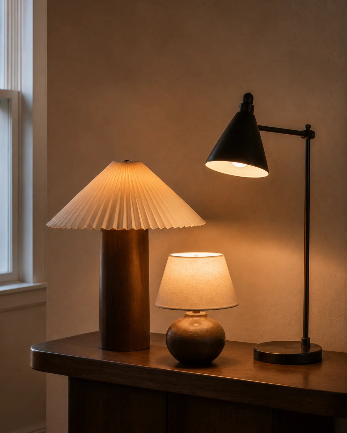 Three warm lamps glowing on a walnut console
